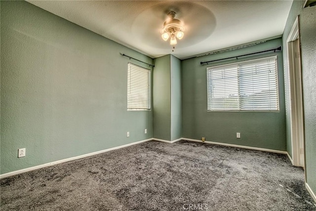 spare room with ceiling fan, plenty of natural light, carpet, a textured wall, and baseboards