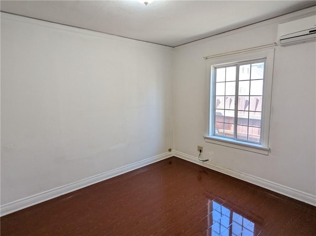 empty room featuring an AC wall unit, dark wood finished floors, and baseboards