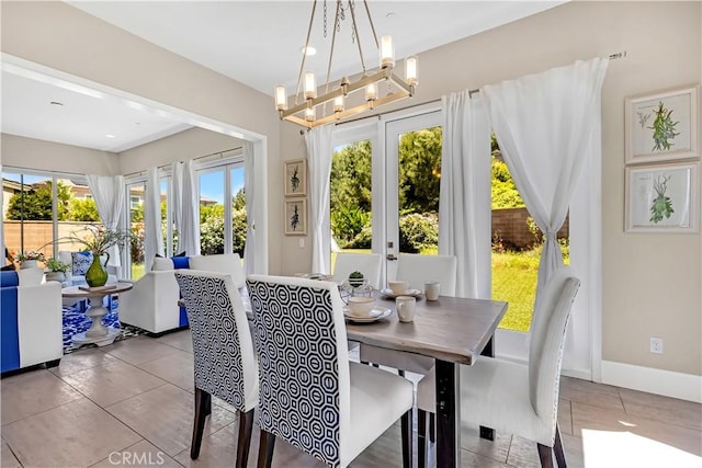 dining area with tile patterned flooring, a chandelier, baseboards, and french doors