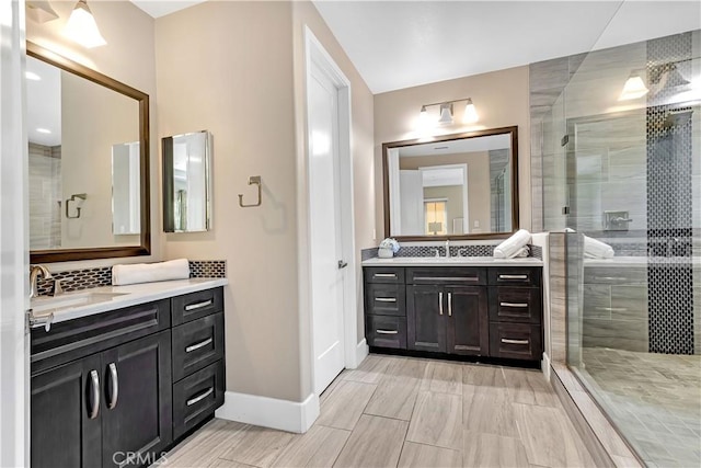 full bath with a shower stall, two vanities, and tasteful backsplash