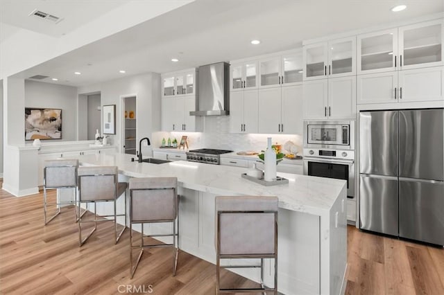 6533 Canyon Oaks Dr, Simi Valley, CA 93063 - kitchen with appliances with stainless steel finishes, wall chimney range hood, a sink, light wood finished floors, and white cabinets