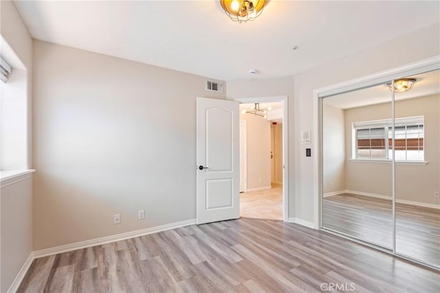 unfurnished bedroom with a closet, wood finished floors, baseboards, and a chandelier