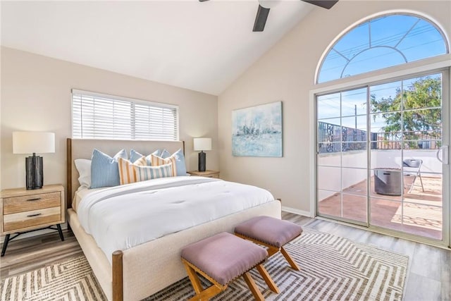 bedroom with access to outside, multiple windows, wood finished floors, baseboards, and high vaulted ceiling