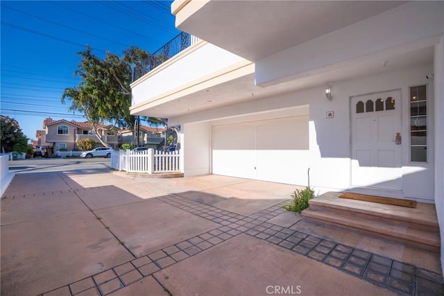 garage featuring fence and concrete driveway