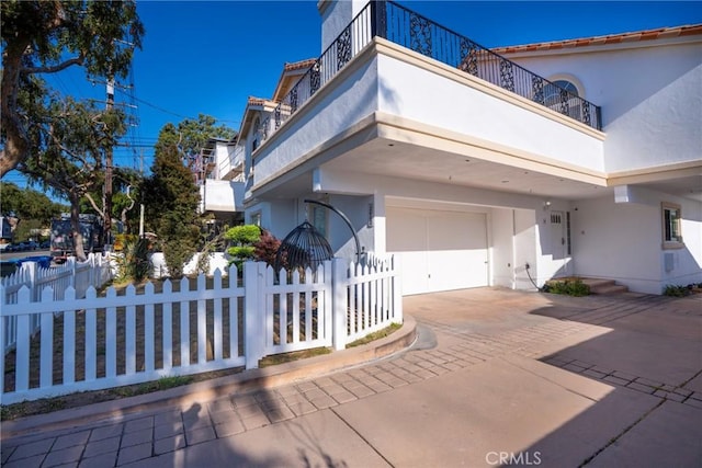 view of front of property featuring stucco siding, a fenced front yard, a garage, and driveway