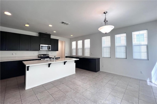 2873 S Via Belamaria, Ontario, CA 91762 - kitchen with stainless steel appliances, dark cabinetry, light countertops, light tile patterned floors, and a breakfast bar area