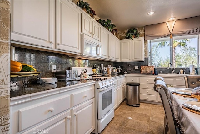 15108 Lighthouse Ln, Lake Elsinore, CA 92530 - kitchen with white appliances, tile countertops, a sink, white cabinets, and decorative backsplash