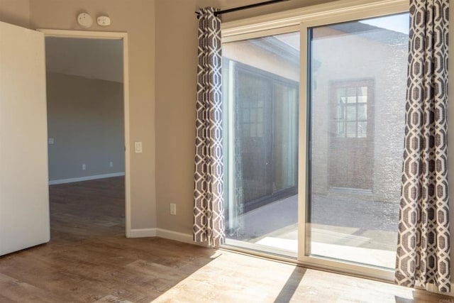 doorway featuring wood finished floors and baseboards