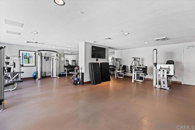 exercise room featuring a textured ceiling and baseboards