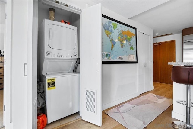 laundry area featuring stacked washer / dryer and light wood finished floors