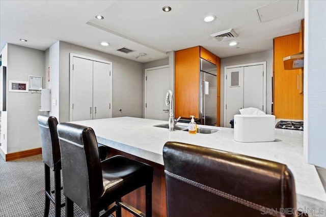 kitchen featuring a sink, appliances with stainless steel finishes, recessed lighting, baseboards, and a breakfast bar area