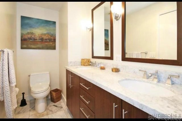 bathroom with toilet and double vanity