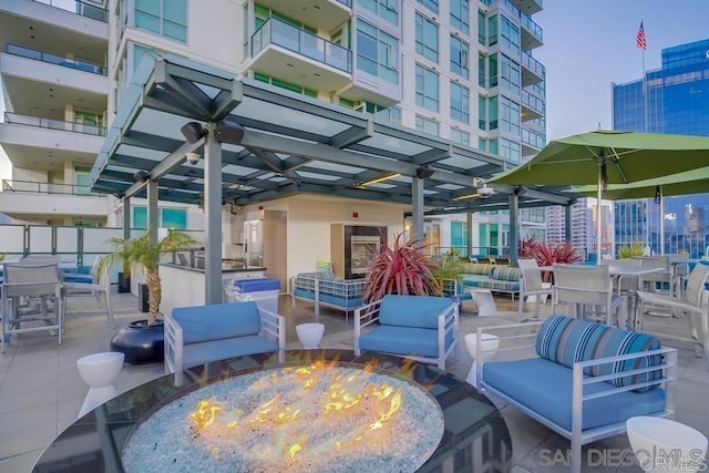 view of patio with an outdoor living space with a fire pit, ceiling fan, and outdoor dining space
