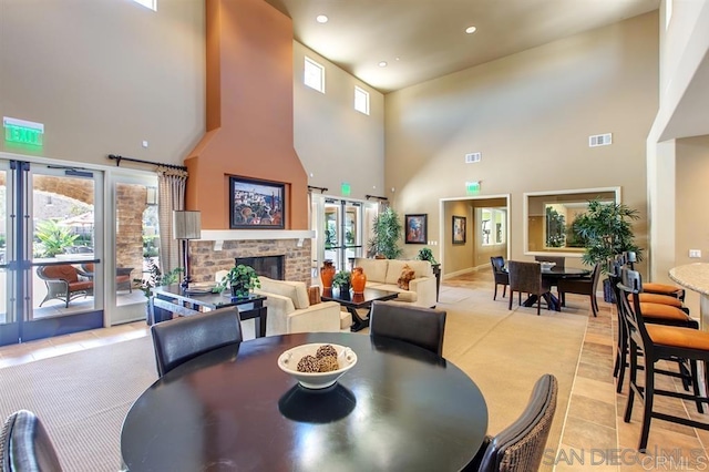 dining room with a high ceiling, a fireplace, light tile patterned floors, recessed lighting, and baseboards