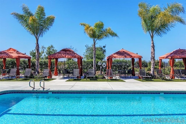 community pool with a gazebo, fence, and a patio
