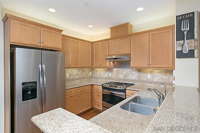 kitchen with stainless steel appliances, under cabinet range hood, a sink, a peninsula, and backsplash