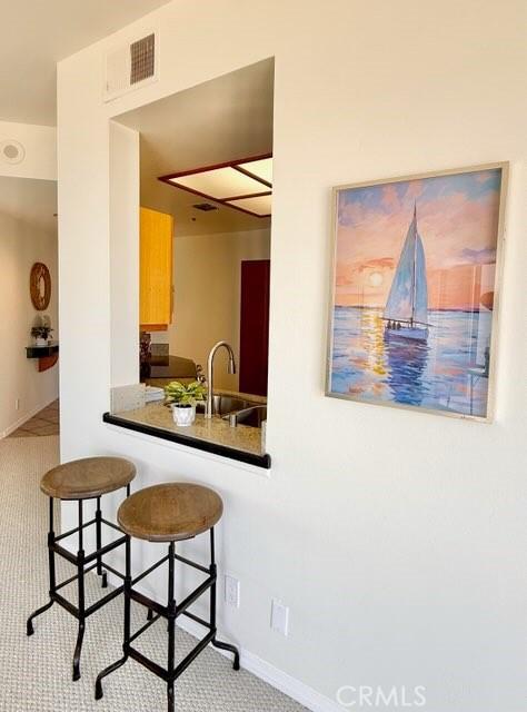 1310 E Ocean Blvd E Unit 1001, Long Beach, CA 90802 - kitchen featuring a sink, dark countertops, baseboards, and a kitchen bar