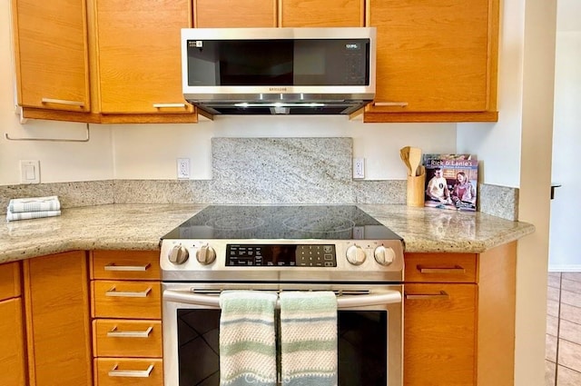 1310 E Ocean Blvd E Unit 1001, Long Beach, CA 90802 - kitchen featuring stainless steel appliances, brown cabinets, light tile patterned floors, and light stone countertops