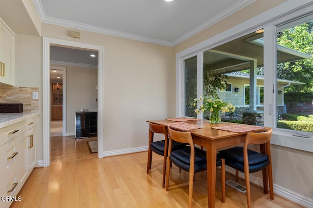 dining area with light wood-type flooring, crown molding, baseboards, and recessed lighting