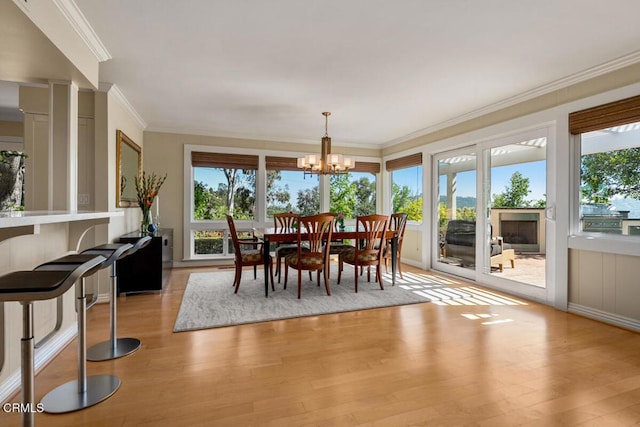 dining area featuring ornamental molding, plenty of natural light, light wood finished floors, and a chandelier