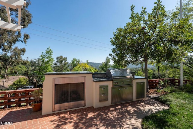 view of patio / terrace with a grill, an outdoor kitchen, and fence