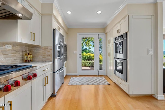 kitchen featuring appliances with stainless steel finishes, under cabinet range hood, recessed lighting, light countertops, and crown molding