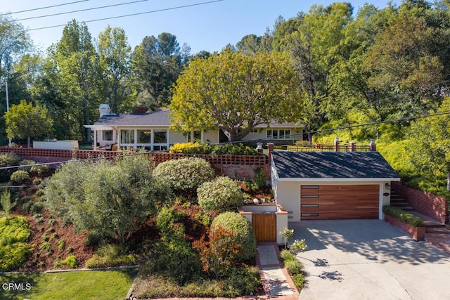 view of front of property with a garage, concrete driveway, and fence