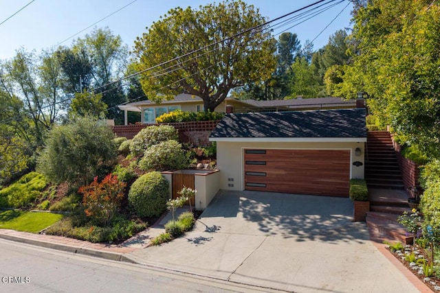 view of front facade featuring stairway, concrete driveway, a garage, stucco siding, and roof with shingles