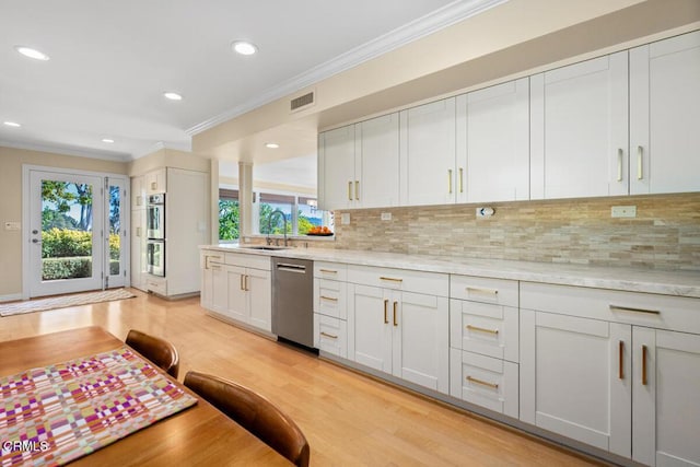 kitchen with appliances with stainless steel finishes, ornamental molding, a sink, light wood finished floors, and backsplash