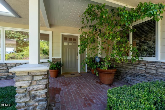 doorway to property featuring stone siding and covered porch
