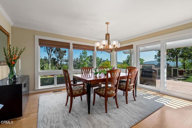 dining area featuring a chandelier, ornamental molding, and light wood-type flooring