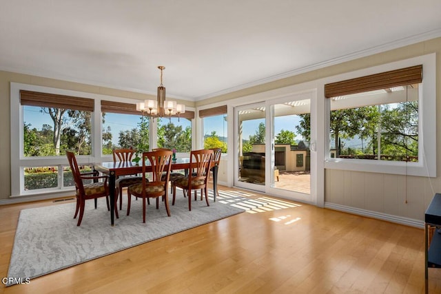 dining space featuring a chandelier, wood finished floors, and ornamental molding