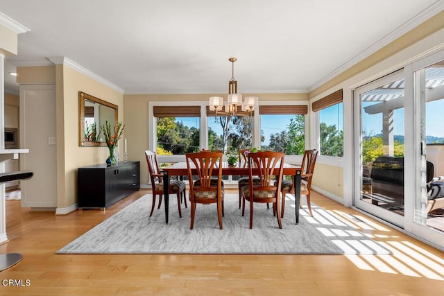 dining area with baseboards, light wood-style floors, a chandelier, and ornamental molding
