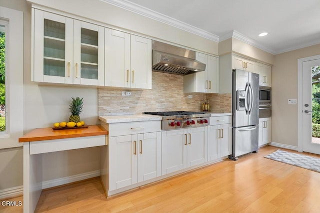 kitchen featuring stainless steel appliances, ventilation hood, light wood finished floors, baseboards, and decorative backsplash