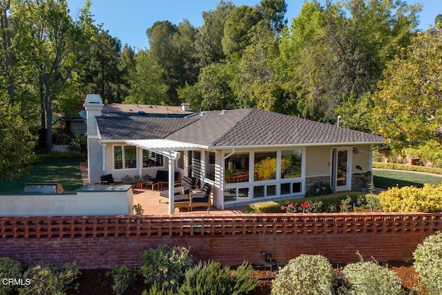 back of property featuring a pergola, a patio area, a chimney, a shingled roof, and stone siding