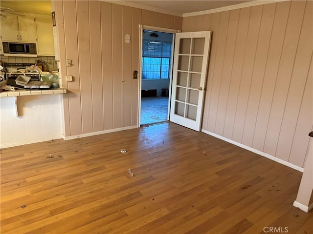 17861 Fresno St, Hesperia, CA 92345 - unfurnished dining area featuring ornamental molding, wood finished floors, french doors, wooden walls, and baseboards