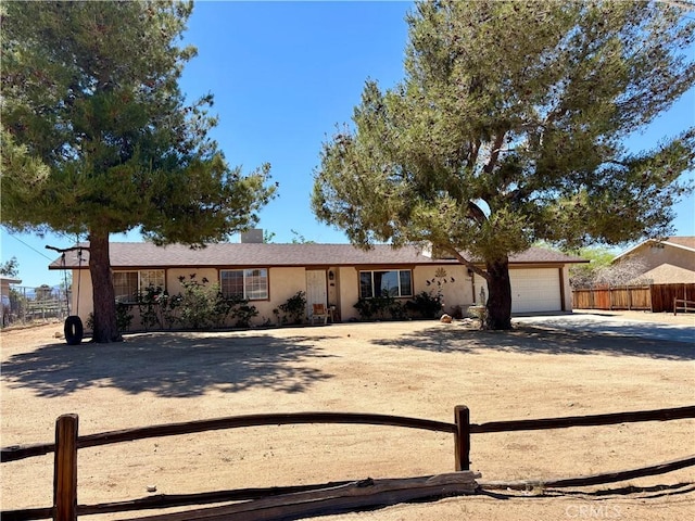 7442 Camarilla Ave, Yucca Valley, CA 92284 - view of front of property with driveway, a garage, fence, and stucco siding