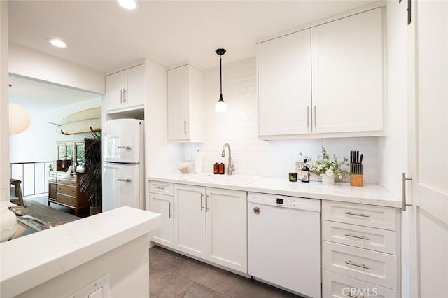 kitchen with white appliances, a sink, tasteful backsplash, white cabinets, and hanging light fixtures