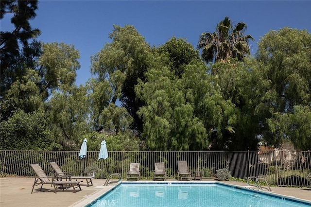 community pool featuring fence and a patio area