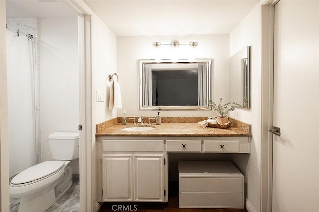 bathroom with toilet, vanity, and baseboards