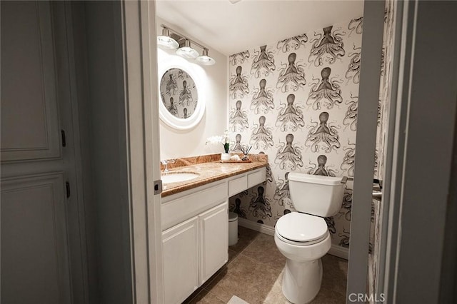half bath with toilet, vanity, tile patterned flooring, and baseboards