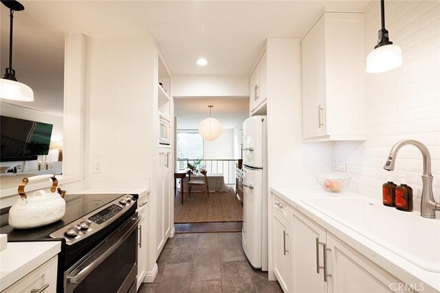 kitchen featuring white appliances, a sink, white cabinets, backsplash, and recessed lighting