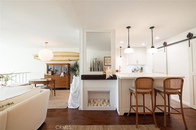 kitchen featuring dark wood-style flooring, recessed lighting, white cabinetry, pendant lighting, and a barn door