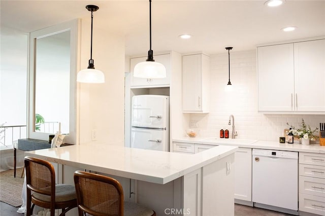 kitchen featuring white appliances, a sink, white cabinetry, and recessed lighting