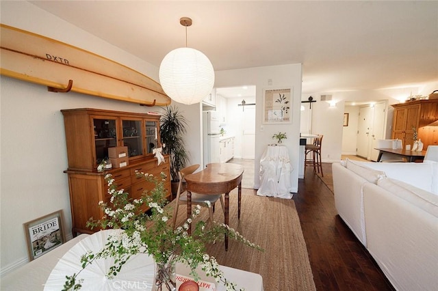 dining area featuring dark wood finished floors, a barn door, and baseboards