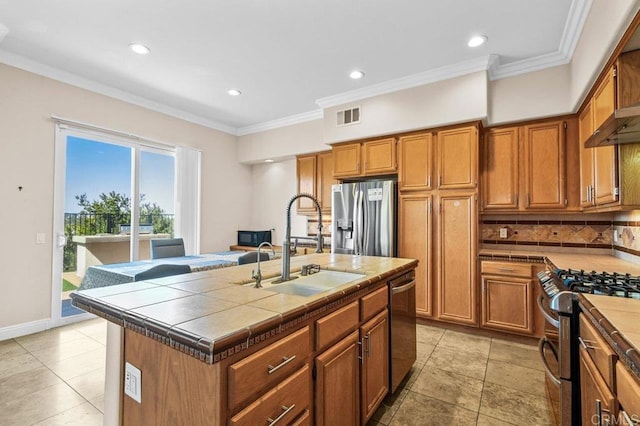 kitchen with appliances with stainless steel finishes, tile counters, brown cabinets, decorative backsplash, and recessed lighting