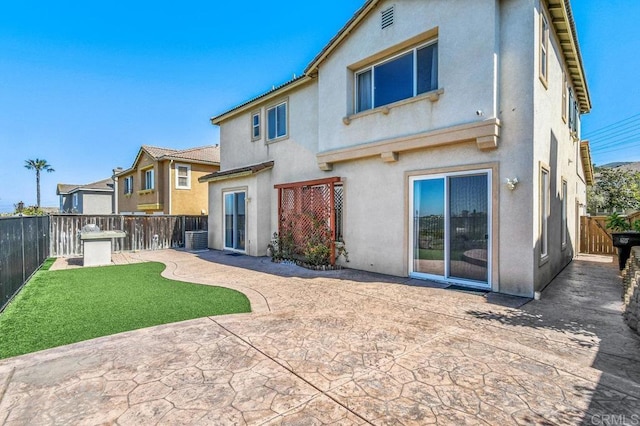 rear view of house featuring a patio area, stucco siding, and central AC unit