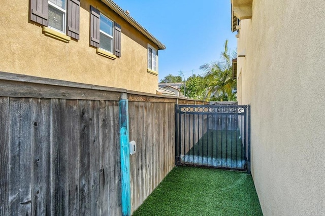view of home's exterior with stucco siding, fence, and a gate
