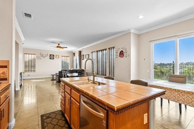 kitchen featuring tile countertops, a sink, stainless steel dishwasher, light tile patterned flooring, and crown molding