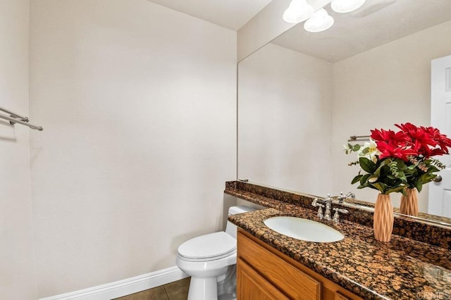 bathroom with baseboards, toilet, tile patterned flooring, and vanity